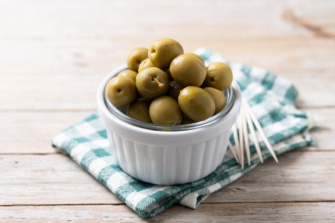 Greek green olives in a bowl on a rustic wooden table