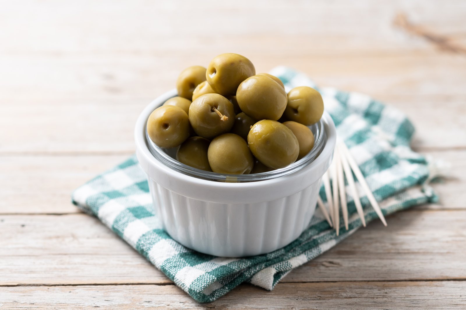 Greek green olives in a bowl on a rustic wooden table